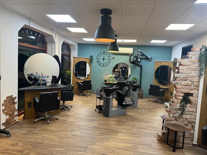 Innenansicht des Salons Friseurleben mit runden Spiegeln, Holzboden und Backsteinwand